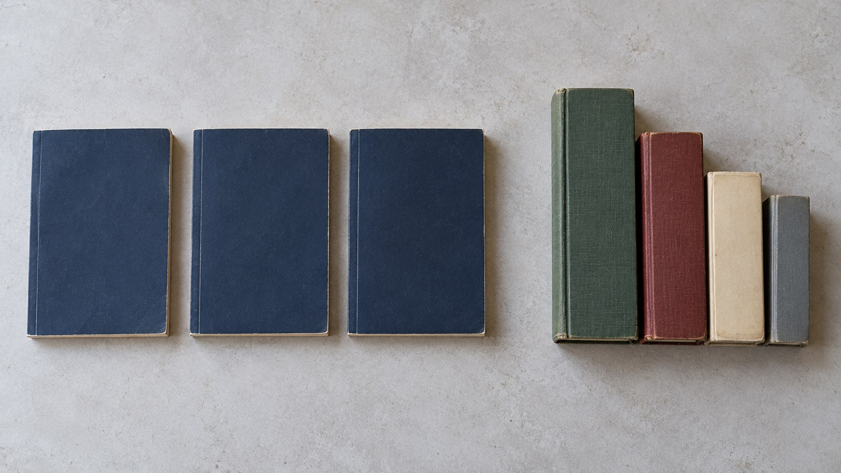 Three matching navy paperbacks beside an assortment of books in different formats.