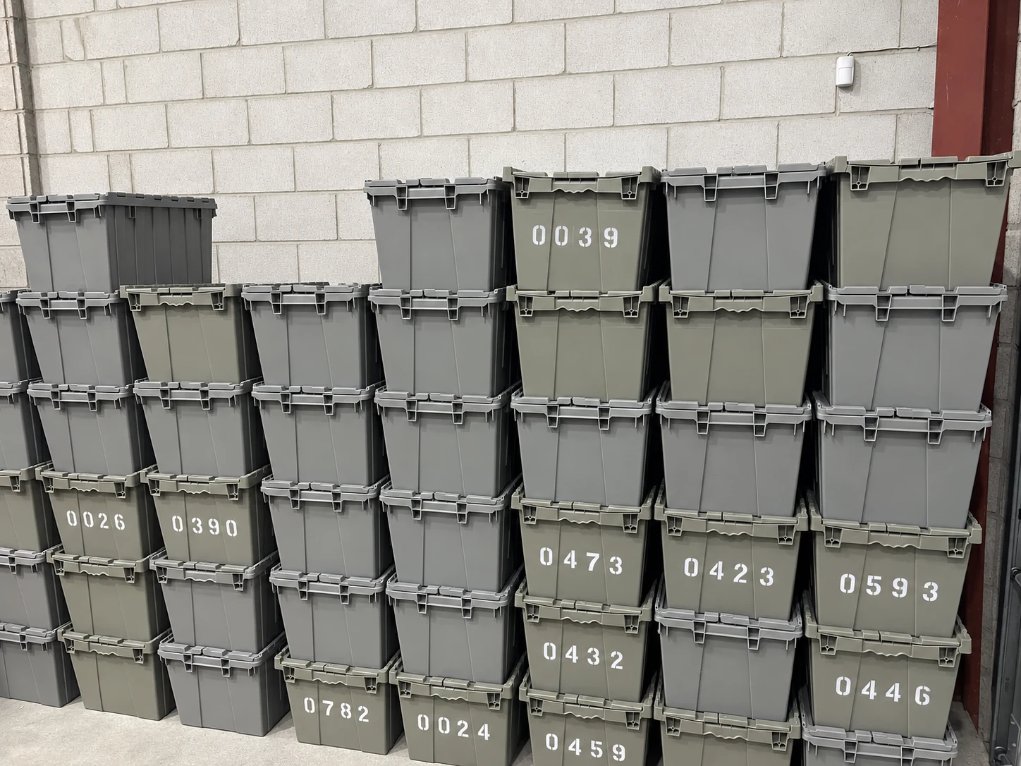 Reusable collection bins stacked neatly against a block wall at the Concord warehouse.